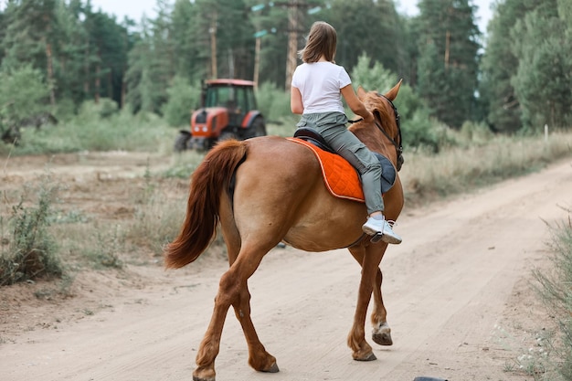 Une fille monte à cheval pendant l'été chaud dans la forêt