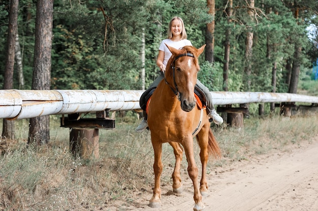 Une fille monte à cheval pendant l'été chaud dans la forêt