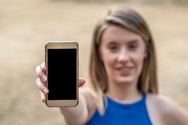 Fille montrant un affichage de téléphone intelligent vierge