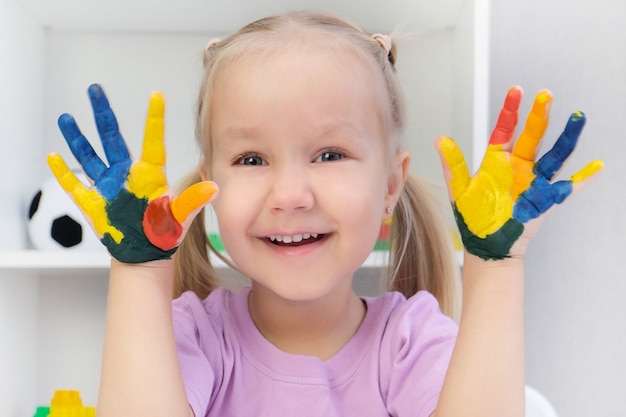 Fille montrant des mains peintes. Mains peintes dans des peintures colorées. Concept d'éducation, d'école, d'art et de peinture