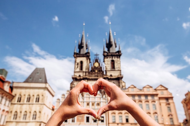 Fille montrant le symbole de l'amour en forme de coeur sur le paysage urbain