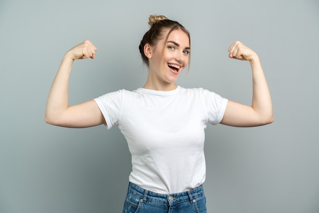 fille montre des muscles isolés sur fond gris