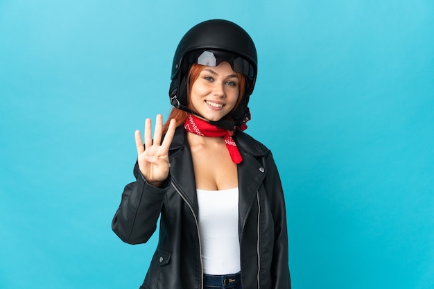 Fille de motard adolescent isolé sur mur bleu heureux et comptant quatre avec les doigts