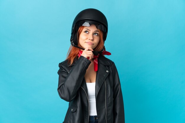 Fille de motard adolescent isolé sur mur bleu et levant