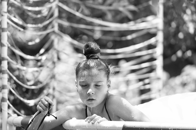 Une fille mouillée s'amuse à se rafraîchir dans la piscine extérieure par une journée d'été ensoleillée.