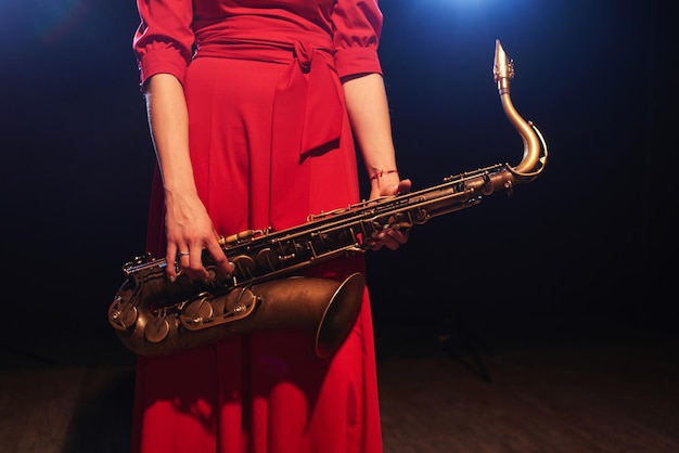 Fille de musicien dans une robe rouge avec un saxophone sur scène