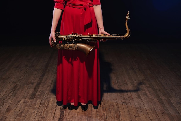 Fille de musicien dans une robe rouge avec un saxophone sur scène