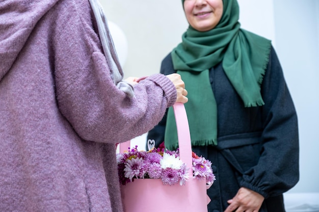 Une fille musulmane arabe offrant à sa mère des roses roses représentent l'amour et le respect