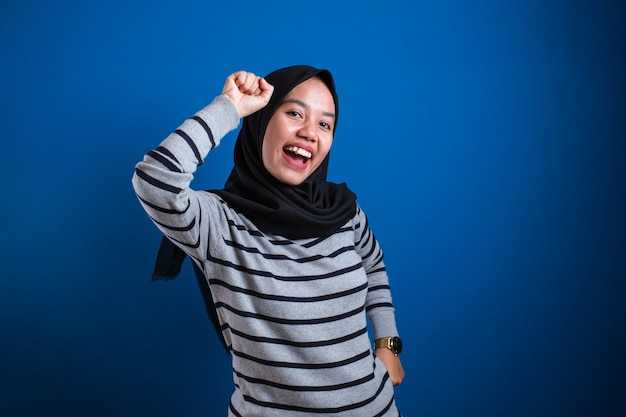 fille musulmane asiatique portant le hijab dansant joyeusement joyeux exprimant la célébration de la victoire de la bonne nouvelle