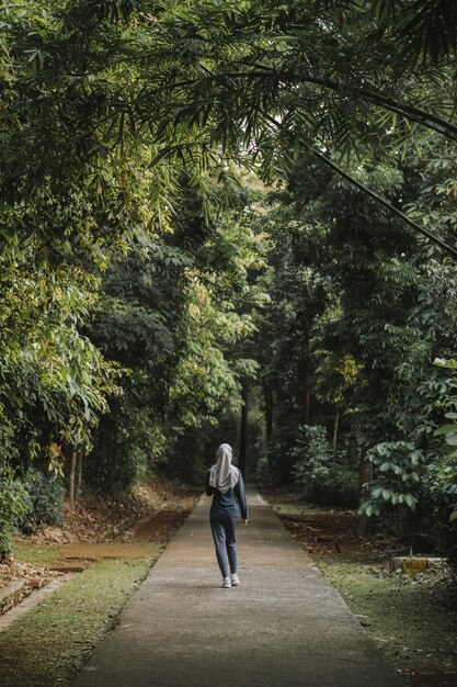 Une fille musulmane fait du jogging le matin entourée d'arbres