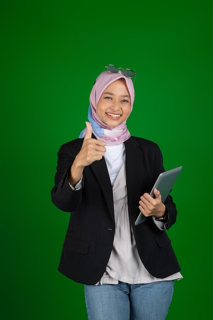 Fille musulmane en hijab à l'aide d'une tablette numérique avec copyspace thumb up