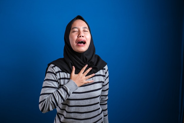 La fille musulmane Hijab est déprimée et triste, elle pleure, elle ferme les yeux et se tient la poitrine en ressentant la douleur