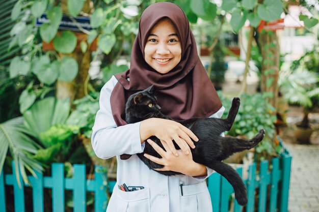 Une fille musulmane sourit avec son chat noir