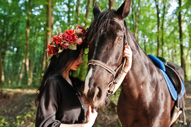 Fille mystique avec un cheval noir en forêt