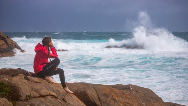 une fille en nattes regarde d'énormes vagues lors d'une tempête sur l'océan dans l'ouest de l'australie