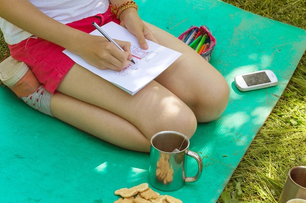 Fille sur la nature s'assoit et dessine Doodle