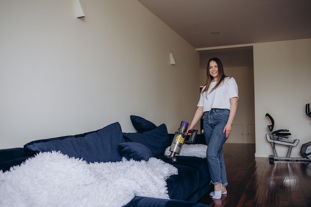 Fille nettoyant le canapé avec un aspirateur