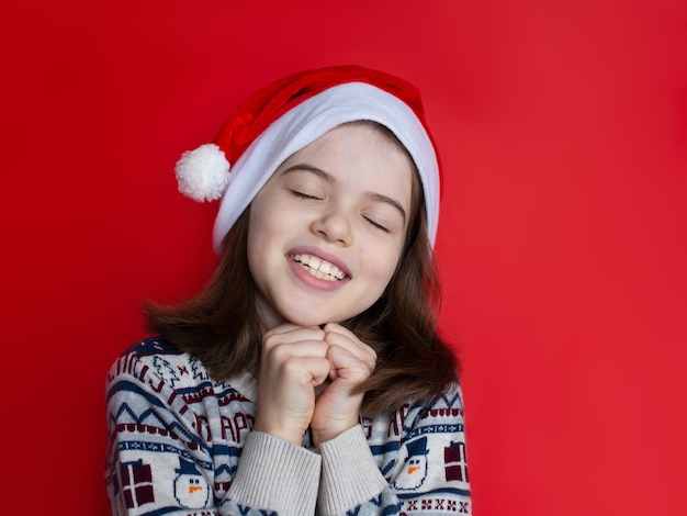 Fille de Noël en bonnet de Noel fait des voeux pour le nouvel an et les rêves de Noël de Noël