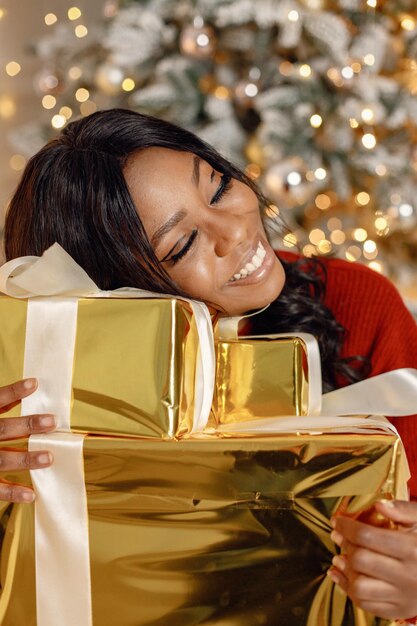 Photo fille noire près du cadeau d'ouverture de l'arbre de noël à la maison