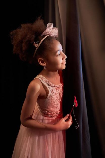 Une fille noire souriante sur scène au théâtre.