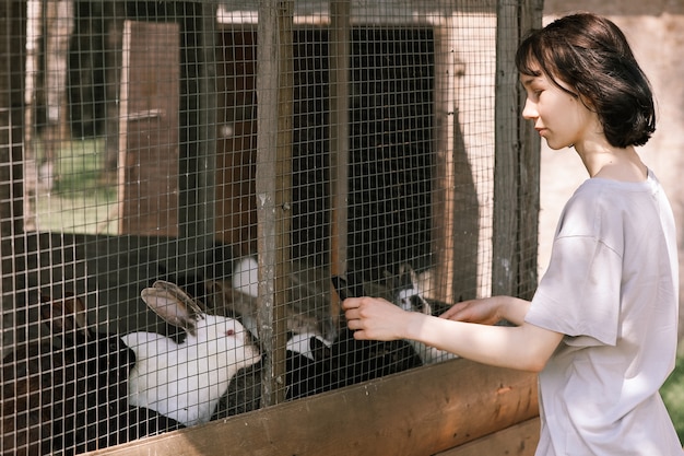 Photo une fille nourrit des lapins dans une ferme