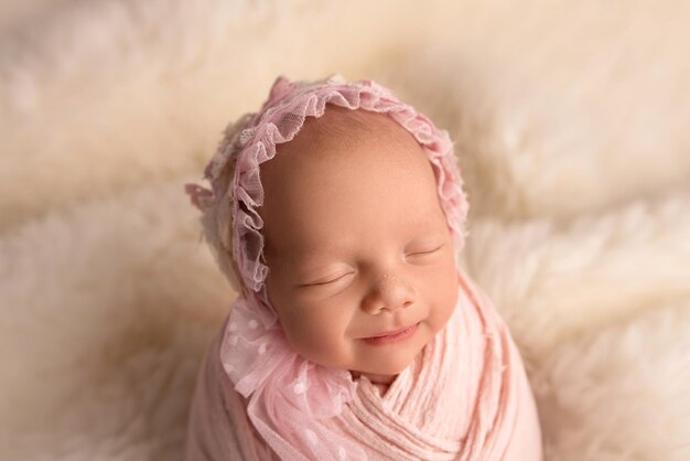 Fille nouveau-née endormie dans les premiers jours de la vie dans un cocon rose avec un bonnet rose sur fond blanc. Macrophotographie en studio, portrait d'un nouveau-né. Le concept de bonheur féminin.