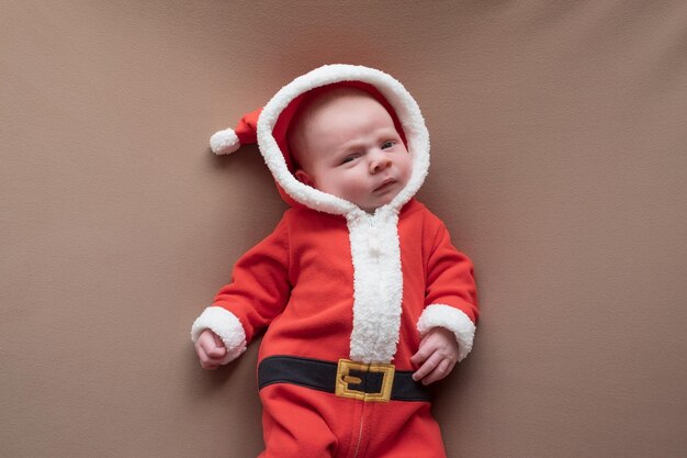 Fille nouveau-née habillée en costume de père noël regardant la caméra avec un visage confus. Concept de Nouvel An ou de Noël.