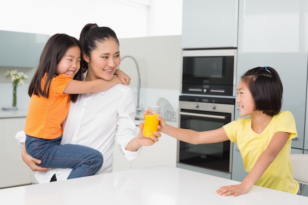 Fille offrant à sa mère un verre de jus d&#39;orange dans la cuisine