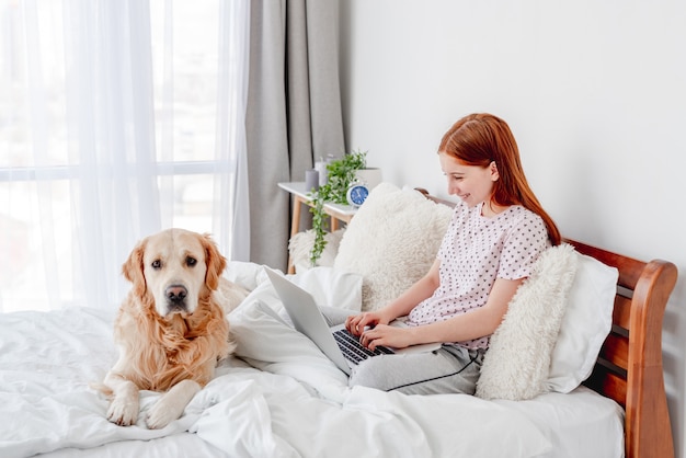 Fille avec ordinateur portable et chien golden retriever