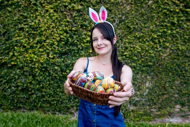 Fille avec des oreilles de lapin de pâques tenant un panier avec des oeufs de pâques colorés mise au point sélective