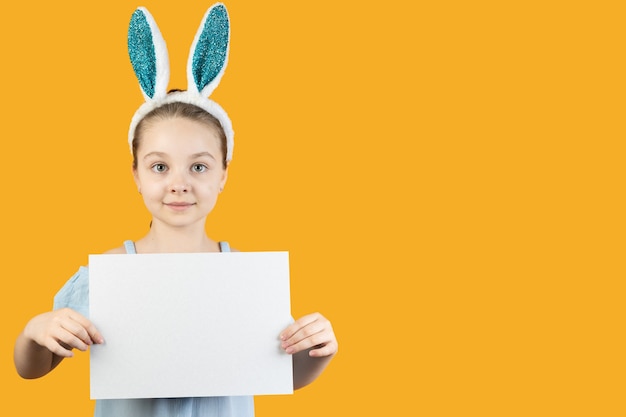 Une fille en oreilles de lapin sur sa tête tient une feuille de carton vierge dans ses mains