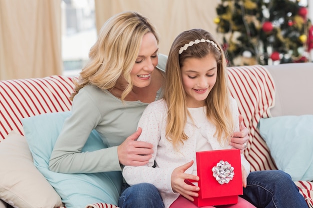 Fille ouvrant le cadeau de Noël avec la mère