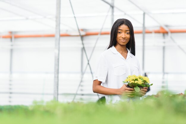 Fille, ouvrière avec des fleurs en serre