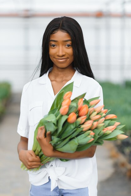 Photo fille, ouvrière avec des fleurs en serre