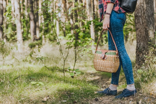 Photo une fille avec un panier à la main marche dans les bois. concept sur le thème des loisirs de plein air.