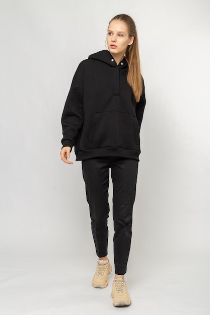 Fille en pantalon cargo noir et sweat à capuche noir isolé sur blanc