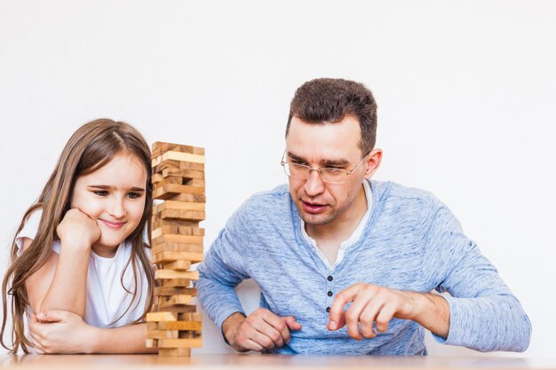 Fille et papa jouent à un jeu à la maison, coûtent une tour de blocs, cubes, jenga, puzzle pour le développement du cerveau, intelligence mentale