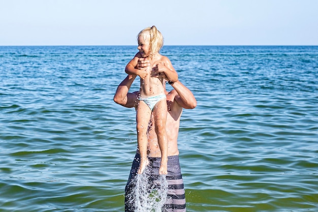 Une fille et un papa joyeux jouent à nager dans la mer.