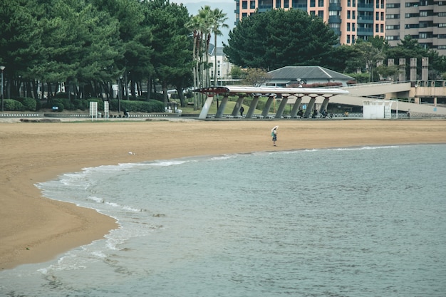 Photo fille avec parapluie attendant et debout sur la plage