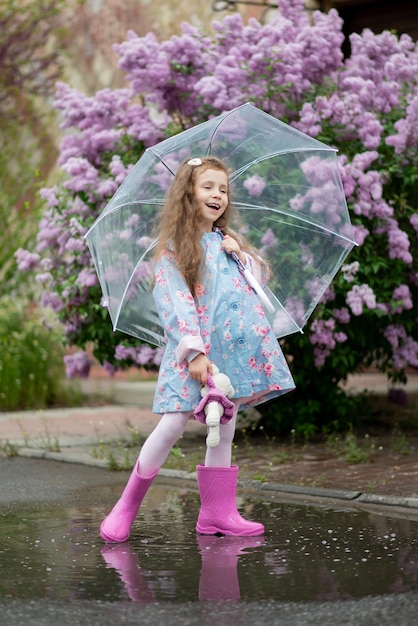 Une fille avec un parapluie transparent sur fond de lilas en fleurs profite du printemps