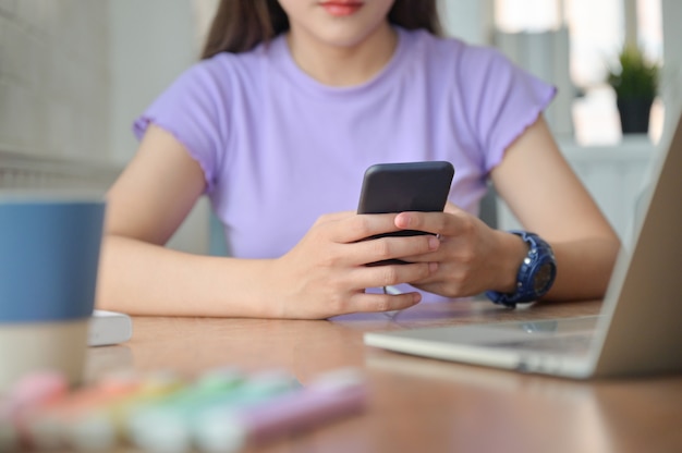 Une fille parle en ligne avec un ami sur un smartphone pendant la pause de l'étude.