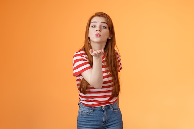 Une fille passionnée rousse mignonne et séduisante envoie des lèvres de pli de caméra de baiser d'air tiennent le bras près de la bouche pour ...