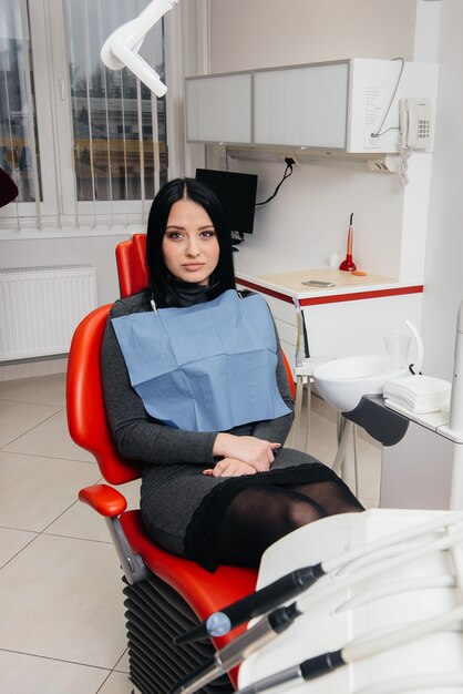 Une fille patiente d'une clinique dentaire est assise sur une chaise et souriant