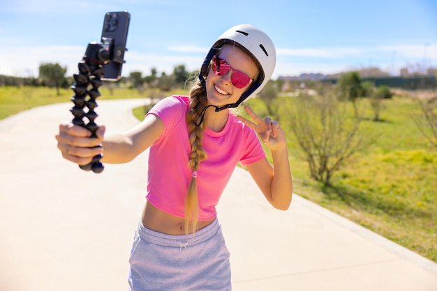 Fille patinant dans le parc et filmant sa vidéo d'action avec un téléphone portable pour la partager sur les réseaux sociaux