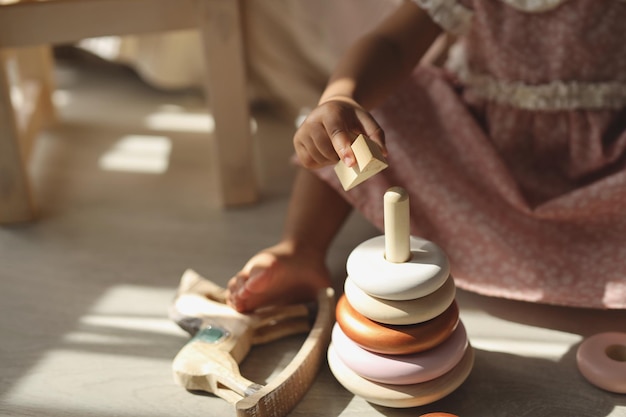 une fille à la peau foncée recueille une pyramide en bois à la maison le concept de respect de l'environnement