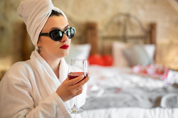 Une fille en peignoir avec un verre de vin