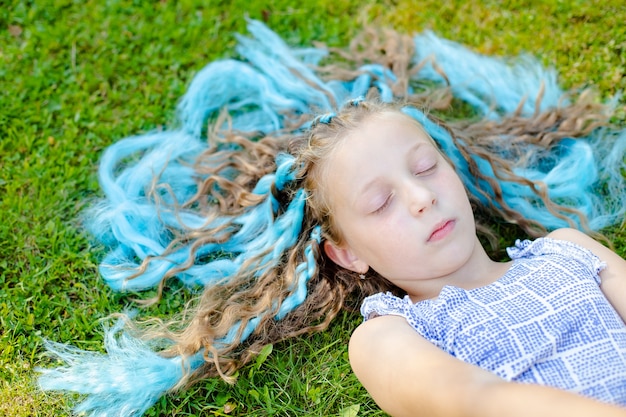 La fille sur la pelouse. Reposez-vous dans la nature. Dormir dans le pré, rêver. Caresser l'herbe