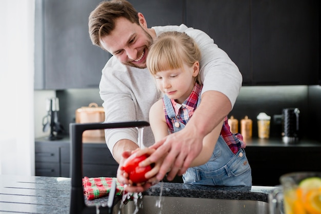 Fille et père lavant le poivre