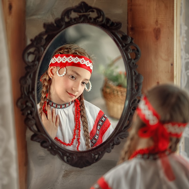 Une fille en perles Rowan regarde dans le miroir et sourit