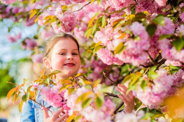Fille petit enfant en fleur de printemps Profitez de l'odeur de la tendre floraison journée ensoleillée Concept de fleur de Sakura Beauté de la fleur magnifique Fille fond de fleur de cerisier Arbre de Sakura en fleurs Parc et jardin